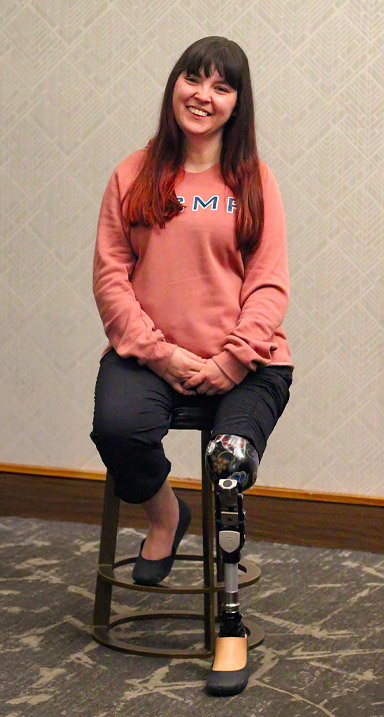 An adult female leg amputee sits on a stool inside a hotel.