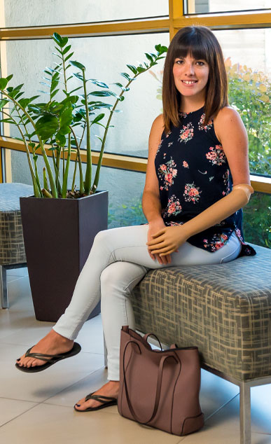 A female adult arm amputee sits on a bench inside.