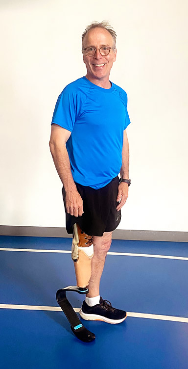 An adult male leg amputee runs on an indoor track.