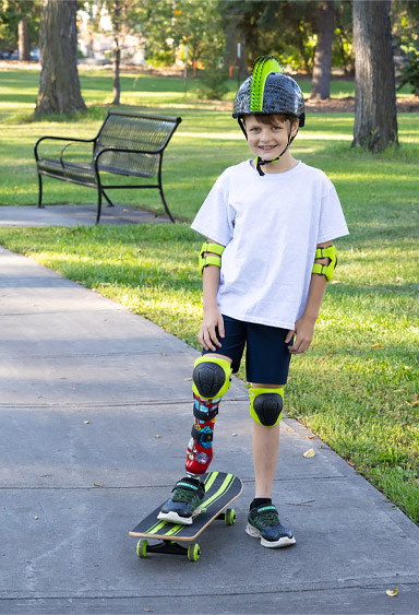 A young male leg amputee skateboards in a park.