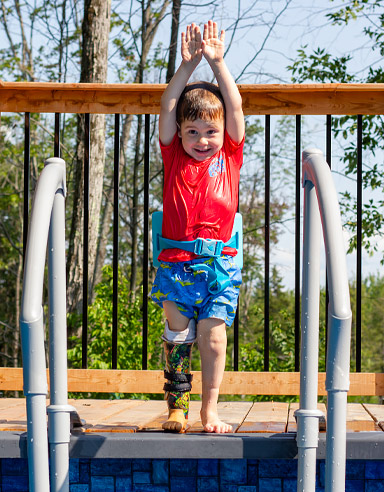 A young male leg amputee prepares to dive into an outdoor pool.