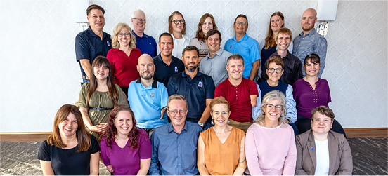 Twenty three adult amputees pose together inside a hotel.