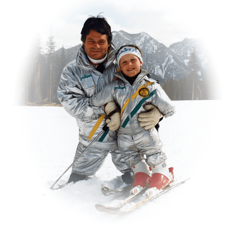 Karl Hilzinger and a child amputee on a ski hill with mountains in the background.