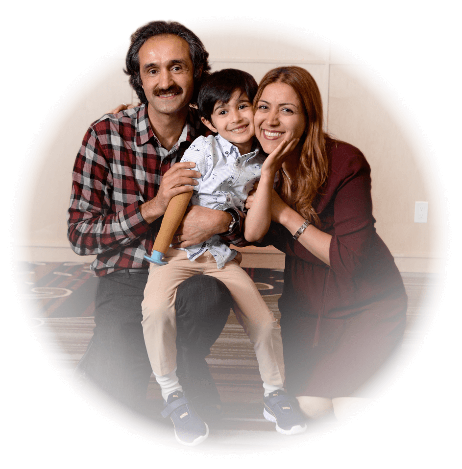 A young male arm amputee sits in between his smiling mother and father.